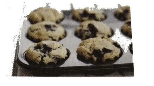 Moule à muffins garni Moule à muffins en métal contenant des muffins aux pépites de chocolat cuits — exercice de maths en 3ème sur les sections de solides et volumes